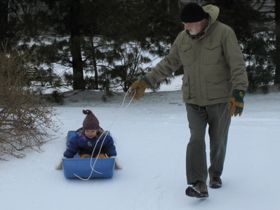 Erika on sled with Grandpa holding rope