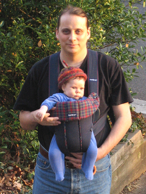 John carrying Erika in Baby Bjorn, Erika wearing knit hat