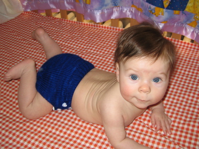 Erika on her stomach in blue diaper, looking up
