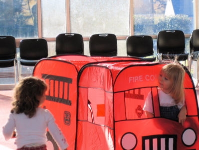 Erika in a toy fire truck with another child looking on
