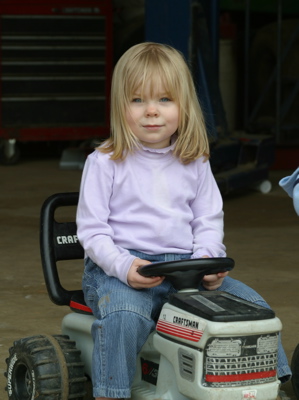 Erika riding on a toy tractor