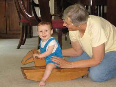 Karl riding a wooden horse,  with Grandma